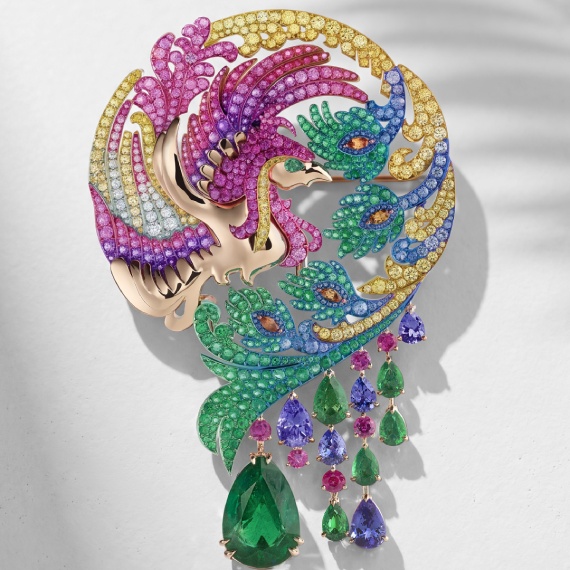 A phoenix-shaped brooch in Ethical rose gold and titanium intertwines emeralds with multicoloured sapphires.